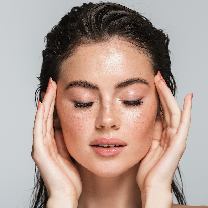 young woman with freckles, eyes closed